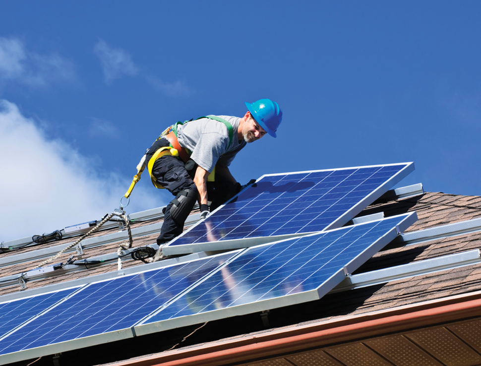 Man installing alternative energy photovoltaic solar panels on roof