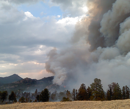 Heavy smoke pouring off a mountain hillside  Dry meadow in foreground 