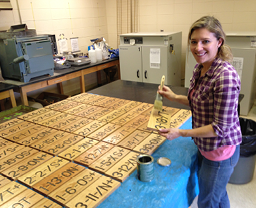 Woman with paint brush applying clear coat to wood signs 